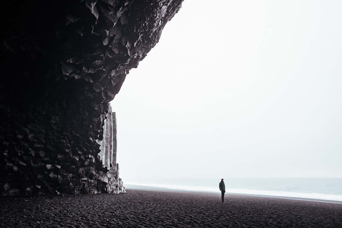 reynisfjara black sand beach person standing on shore during daytime white